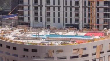 Yüzme havuzu inşaatı, otoparkın çatısındaki son aşamada birçok işçinin uçuş saatiyle birlikte. Dubai 'de yeni bir gökdelen inşaatı