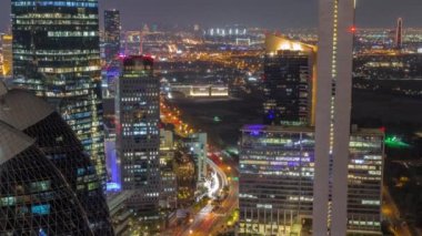 Dubai hava sahasının yoğun kavisli yolundaki yüksek katlı binaların gökyüzü manzarası tüm gece sürüyor, BAE. Uluslararası Finans Merkezi 'nde yukarıdan aydınlatılmış ofis gökdelenleri
