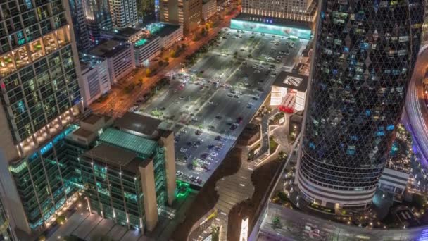 ドバイの空中夜のタイムラプス UaeのシェイクZayed Roadの高層ビルに囲まれた大きな駐車場のスカイラインビュー 上から国際金融センターのライトアップされた高層ビル — ストック動画