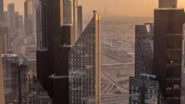 Dubai 'deki Sheikh Zayed Yolu' ndaki yüksek binalar. Gün batımında uluslararası finans bölgesinde gökdelenler. Arka planda evler ve villalar var. Turuncu ışık