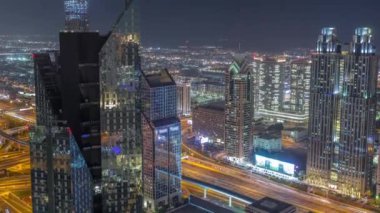 Dubai 'deki Sheikh Zayed Yolu' ndaki yüksek binalar gece uçuşları, BAE. Uluslararası finans bölgesinde yukarıdan aydınlatılmış gökdelenler. Arka planda evler ve villalar var.