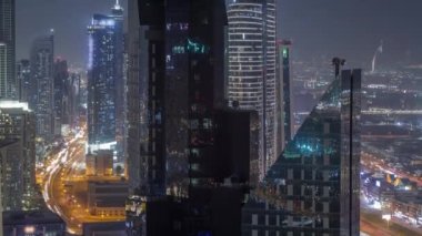 Dubai 'deki Sheikh Zayed Yolu' ndaki yüksek binalar gece uçuşları, BAE. Uluslararası finans bölgesindeki gökdelenler ve yukarıdan iş sahası. Arka planda evler ve villalar