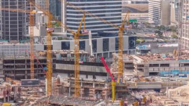 Çalışan vinçleri olan büyük bir inşaat alanı. Business Bay, Dubai 'deki büyük yerleşim ve ofis alanının en iyi hava görüntüsü. Takviyeli üniformalı işçiler