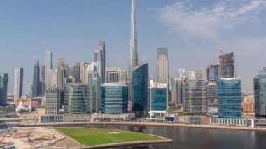 Dubai Business Bay ve şehir merkezinin havadan görüntüsü. Kanal zamanındaki çeşitli gökdelenler ve kuleler. Vinçleri olan bir inşaat alanı. Gölgeler hızlı hareket ediyor