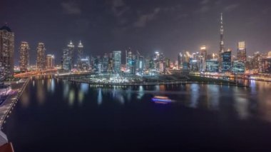 Hava panoramik görüntüsü Dubai Business Bay ve Downtown 'a. Kanal boyunca çeşitli gökdelenler ve kuleler var. Vinçleri olan büyük bir inşaat alanı.