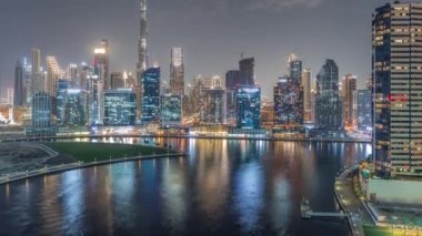 Dubai Business Bay ve şehir merkezinin havadan görüntüsü. Kanal boyunca çeşitli gökdelenler ve kuleler var. Vinçleri olan bir inşaat alanı. Sudaki yansıma