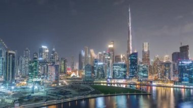 Dubai Business Bay ve şehir merkezinin havadan görüntüsü. Kanal boyunca çeşitli gökdelenler ve kuleler var. Adada vinçleri olan bir inşaat alanı.