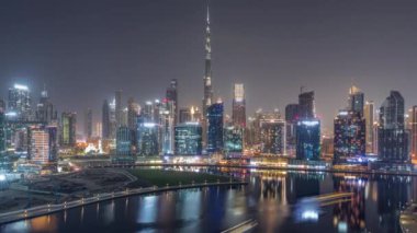 Tüm gece boyunca Dubai Business Bay ve Downtown 'ın havadan görüntüsü. Kanal boyunca çeşitli gökdelenler ve kuleler var. Vinçli inşaat alanı