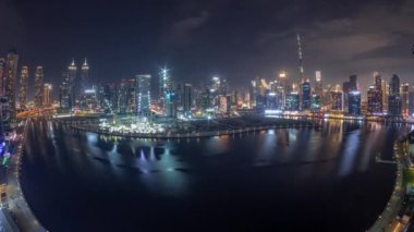 Dubai Business Bay ve Downtown 'ın tüm gece boyunca çeşitli gökdelenleri ve kuleleri olan hava panoraması kanal gece zaman çizelgesi boyunca uzanır. Vinçleri sis kaplı inşaat alanı