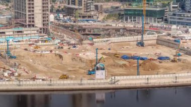 Apartman kompleksinin hava zaman ayarlı inşaatı için temel çukurunda yığın sürüşü. Kazı makineleri, vinçler, buldozerler ve kamyonlar olarak derin kurulum ve kazılar, Dubai