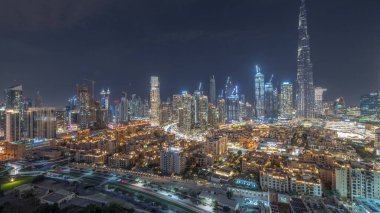 Dubai Downtown panorama day to night transition with tallest skyscraper and other towers view from the top after sunset in Dubai, United Arab Emirates. Lights turning on.