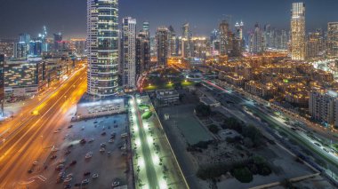Dubai 'nin iş yeri kulelerinin panoramik görüntüsü günden geceye geçiş. Gün batımından sonra inşaat halindeki bazı gökdelenlerin ve yeni binaların çatı manzarası