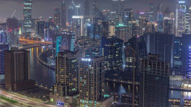 Dubai iş sahası kulelerinin modern mimarisine sahip Skyline 'dan geceye geçiş. Gün batımından sonra kanal ve şantiyeli hava manzarası