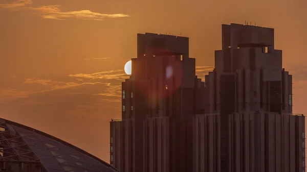 ドバイ国際金融センター超高層ビル上空の日没 背の高い塔と背景のオレンジ色の空の後ろに太陽が沈む — ストック写真