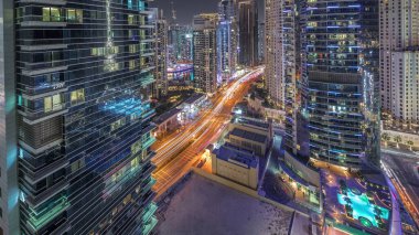 Panorama showing Dubai Marina and JBR area and the famous Ferris Wheel aerial night and illuminated skyscrapers and traffic on streets