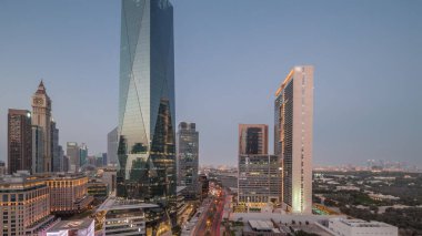 Dubai Uluslararası Finans Bölgesi, günden geceye geçiş. Gün batımından sonra panoramik ofis kulesi manzarası. Şehir merkezine yakın bir yolda otelleri ve trafiği olan gökdelenler.