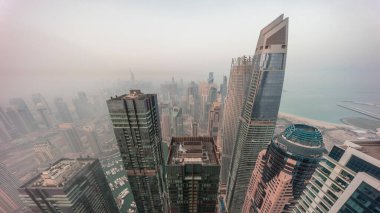 Dubai Marina 'nın gökdelenlerle çevrili kanalı gece gündüz kıyı şeridi boyunca uzanan panoramik görüntüsü. Güneş doğmadan önce sisli bir hava. Dubai, BAE