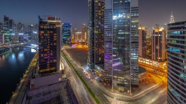 Dubai Business Bay 'deki ve şehir merkezindeki gökdelenlerin şehir manzarası. Su kanalından geceye geçiş günü. Günbatımından sonra kuleleri ve rıhtımı olan modern gökyüzü. Uluslararası bir iş merkezi.