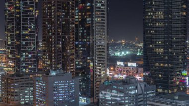 Modern mimari zaman çizelgesi olan Business Bay bölgesi ufuk çizgisi. Dubai gökdelenleri ve ana karayolu yakınlarındaki aydınlık kulelerin havadan görüntüsü. Çok katlı otoparklar ve pencerelerde ışık