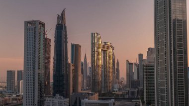 Dubai şehir merkezi ve finans bölgesinde caddelerde trafiği olan fütürist kuleler ve gökdelenler. Şehir silueti, gün doğumunda havadan sabah saatleri. Sıcak ışık ve güneş camdan yansıyor.