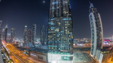 Modern mimari zaman çizelgesiyle gökyüzüne yükselen Business Bay District Panorama. Dubai gökdelenleri ve ana karayolu yakınlarındaki aydınlık kulelerin havadan görüntüsü. Kavşakta trafik vardı.