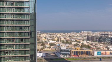 Dubai Şehir Yürüyüşü 'nün hava görüntüsü hızla hareket eden gölgelerle gökdelen zaman aralığının arkasına bakıyor. Avrupa tarzı yaratılmış düşük katlı binalar ve villalar. Şeyh zayed yolu ve metro trafiği