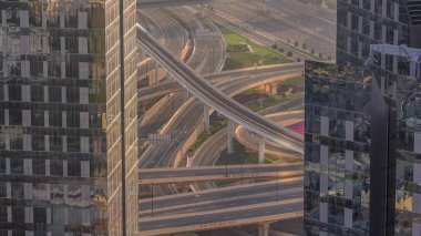 Gökdelenler arasındaki hava manzarası gün batımında Dubai şehir merkezindeki metro hattı ile yoğun bir yol kavşağı. Arabalar ve kamyonlar her iki yöne doğru ilerliyor..