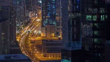 Hava görüntüsü Dubai 'deki yoğun kavşaklara gece gündüz geçiş zamanı. Gün doğmadan önce otoyolun her iki tarafına doğru giden arabalar var. İş bölgesi gökdelenleri