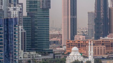 Alışveriş merkezi yakınlarındaki yeni beyaz cami Business Bay hava sahasındaki gökdelenlerle çevrili. Gün batımından sonra gece geçiş zamanı. Otoparkın yanındaki yolda trafik vardı.