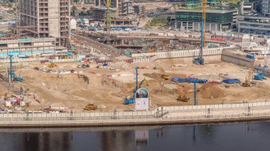 Apartman kompleksinin hava zaman ayarlı inşaatı için temel çukurunda yığın sürüşü. Kazı makineleri, vinçler, buldozerler ve kamyonlar olarak derin kurulum ve kazılar, Dubai