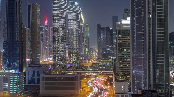 ドバイのダウンタウンや金融街の路上で忙しいトラフィックと未来的な塔や照明高層ビル 都市のスカイライン空中夜のタイムラプス — ストック写真