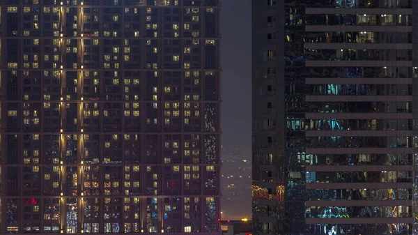 多くの輝く窓のあるフラットの背の高いブロックは 都市空中のタイムラプスの住宅地に位置しています 大きな塔や高層ビルの部屋の夜の光 — ストック写真