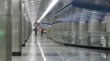 Nakil koridoru zaman ayarlı modern bir metro istasyonu. İstasyonlar arasında yürüyen insanlar