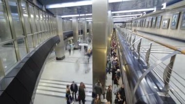 Trenlerin zaman ayarlı olduğu modern bir metro istasyonu. Platformda bekleyen insanlara tepeden bakmak