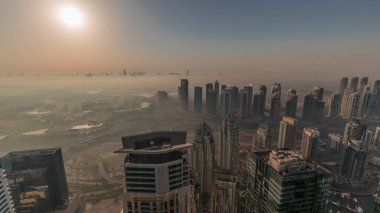 Dubai Marina Panoraması, güneş doğarken JLT gökdelenleri ve golf sahası, Dubai, Birleşik Arap Emirlikleri. Yukarıdan hava manzarası sisli bir sabah. Turuncu gökyüzü ile şehir silueti