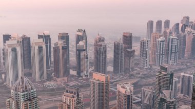 Şeyh Zayed Yolu yakınlarındaki JLT gökdelenleri ve marina kuleleri gece gündüz geçiş yapıyor. Aydınlatılmış konut binaları ve villalarla ufuk çizgisi. Güneş doğmadan önce sisli bir sabah