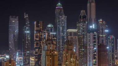 Dubai Marina 'nın gökdelenleri tüm gece boyunca parlayan ve yanıp sönen pencereli en yüksek konutlu binalar. JLT bölgesinden hava üst görünümü