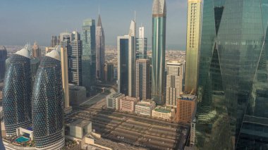 Dubai 'nin finans merkezi lüks gökdelenleri ve büyük park sabahı, Dubai, Birleşik Arap Emirlikleri. Ofis kuleleriyle hava manzarası ve güneş doğarken cam yüzeyden yansımalar