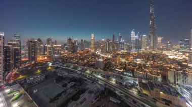 Dubai Downtown day to night transition with tallest skyscraper and other towers panoramic view from the top during sunset in Dubai, United Arab Emirates. Lights turning on.