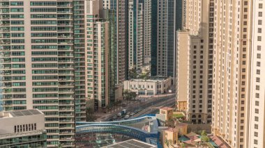 JBR ve Dubai Marina gökdelenleri, deniz kenarındaki apartman daireleri ve modern gökdelenlerle gökyüzü. Gün doğarken kavşakta trafik ve yaya köprüsü.