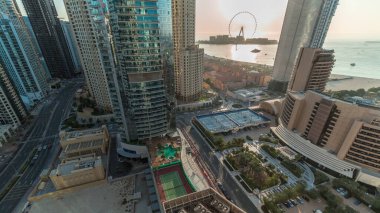 Dubai Marina ve JBR bölgesinin panoramik manzarası ve ünlü dönme dolabın havası. Basra Körfezi 'ndeki altın kumsallar gün boyunca gölgeler hızla ilerliyor..