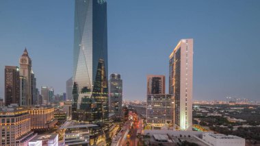 Dubai Uluslararası Finans Bölgesi, günden geceye geçiş. Gün batımından sonra panoramik ofis kulesi manzarası. Şehir merkezine yakın bir yolda otelleri ve trafiği olan gökdelenler.