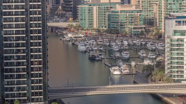 Birçok yat ve tekne bütün gün boyunca liman havasında park halindedir ve gölgeler hızla hareket eder. Dubai Marina rıhtımı yürüyüş alanı. Modern tekne derede yüzüyor..