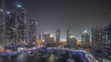 Panorama, liman gecesinde Dubai marinasının en yüksek gökdelenlerini ve yatlarını gösteriyor. Apartman binalarına, otellere ve ofis bloklarına, BAE 'nin modern yerleşim alanlarına bak