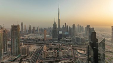 Panorama showing aerial view of tallest towers in Dubai Downtown skyline and highway before sunset. Financial district and business area in smart urban city. Skyscraper and high-rise buildings