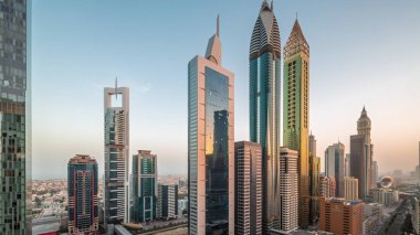 Dubai Uluslararası Finans Bölgesi 'nin birçok gökdelenli sabah manzarası. Metro istasyonu yakınlarındaki bir yolda trafik ve çatısı yüzme havuzlu çok katlı bir otopark. Dubai, BAE.