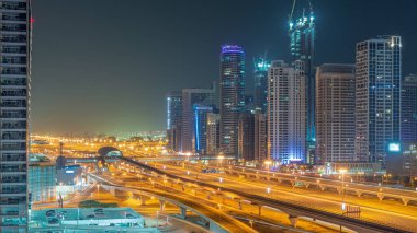 Dubai Marina gökdelenleri ve tüm gece boyunca metro antenli Şeyh Zayed yolu. Yanıp sönen pencereleri olan modern kulelerin yakınındaki bir otoyolda trafik vardı. Birleşik Arap Emirlikleri.