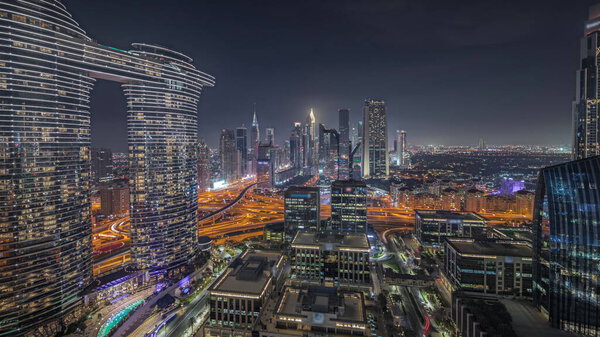 Panorama showing futuristic Dubai Downtown and finansial district skyline aerial night. Many illuminated towers and skyscrapers with traffic on streets