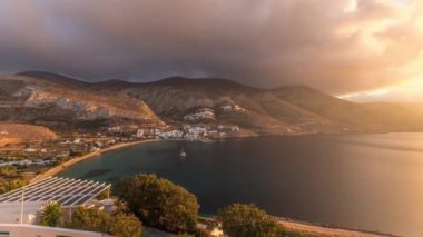 Panorama, Amorgos adasında gün batımında turuncu bulutları gösteriyor. Geleneksel Yunanistan - tepelerde beyaz evler ve turkuaz deniz, Kiklad