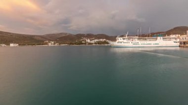 Panorama, Amorgos adasının akşam saatlerini gösteriyor. Gün batımında. Geleneksel Yunanistan - tepelerdeki beyaz evler ve limandaki limandaki gemi, Kiklad